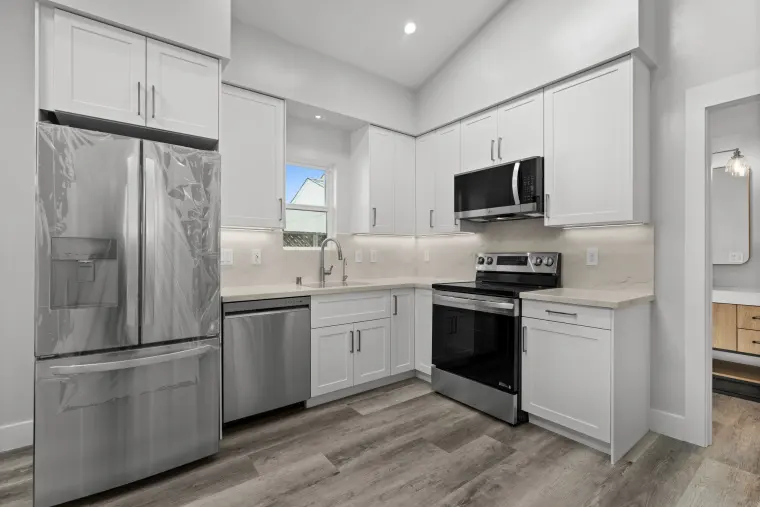 Kitchen with white shaker cabinets, stainless French-door refrigerator, dishwasher and range, and quartz counters