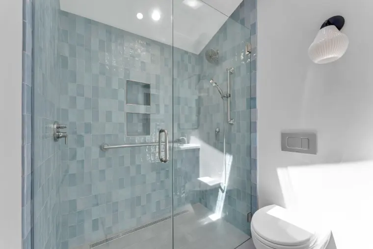 Walk-in shower tiled in blue-green glazed tile with a built-in niche