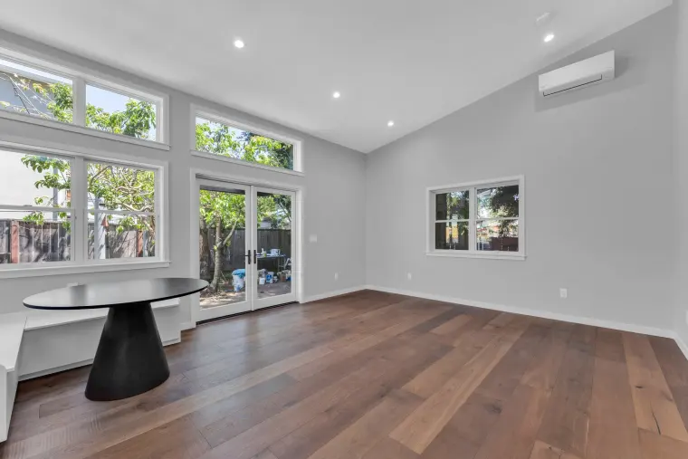 Studio with clerestory and French-door windows along one wall, a built-in bench nook with round table, and oak flooring