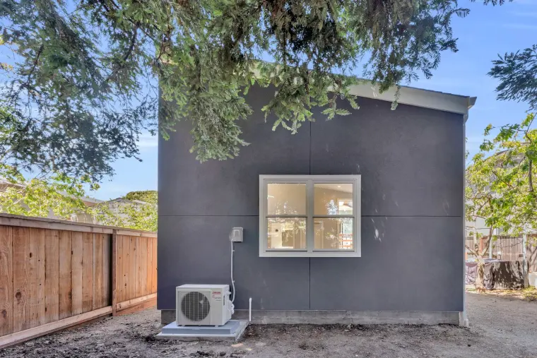 Back of the ADU with a single window and the mini-split condenser along the fence
