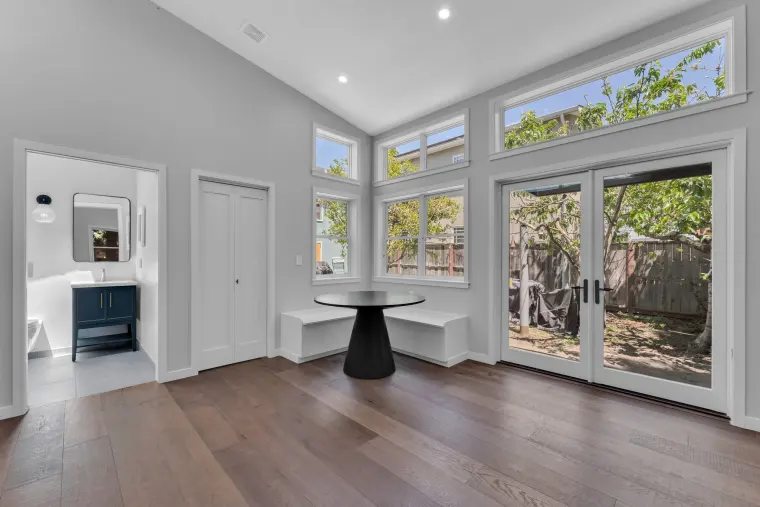 Great room under a vaulted ceiling with clerestory windows, a round dining table, and built-in window bench