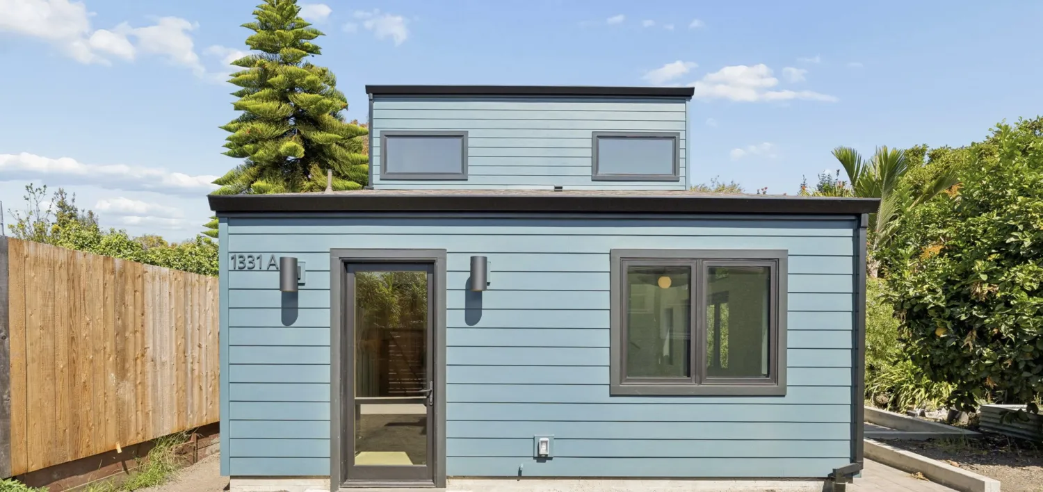 Two-story ADU in blue lap siding with black windows and a glass front door