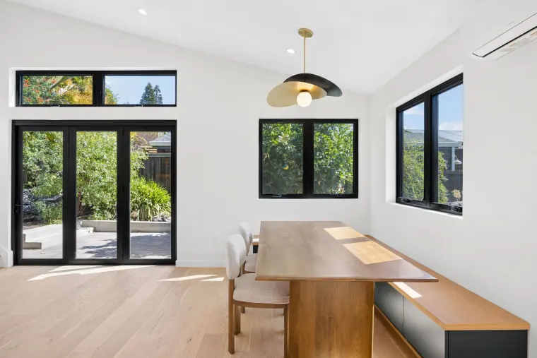 Dining table in front of black French doors and a high window