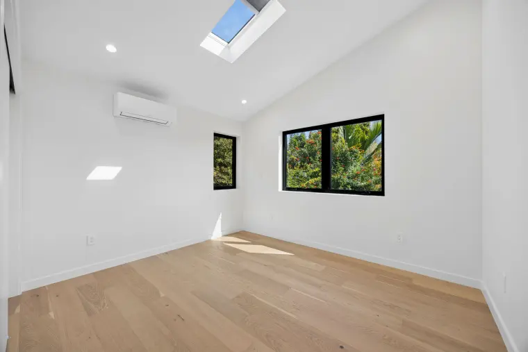 Room with a vaulted ceiling, a skylight, and black-framed windows