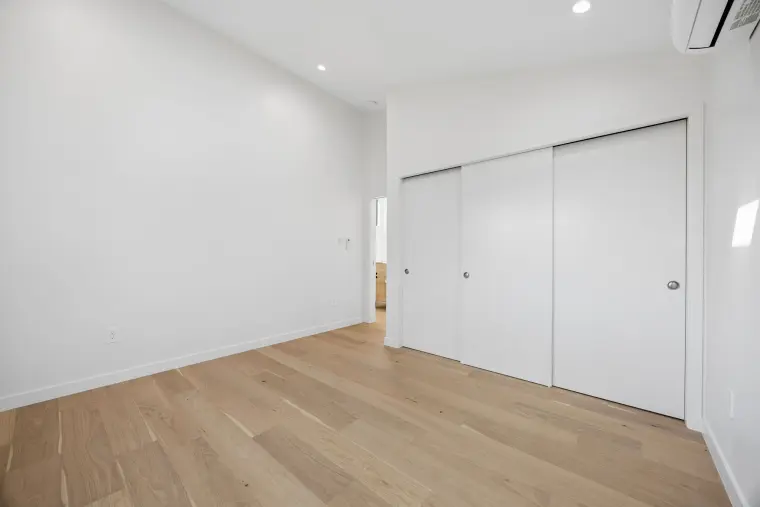 Bedroom with a three-panel sliding closet and light oak floors