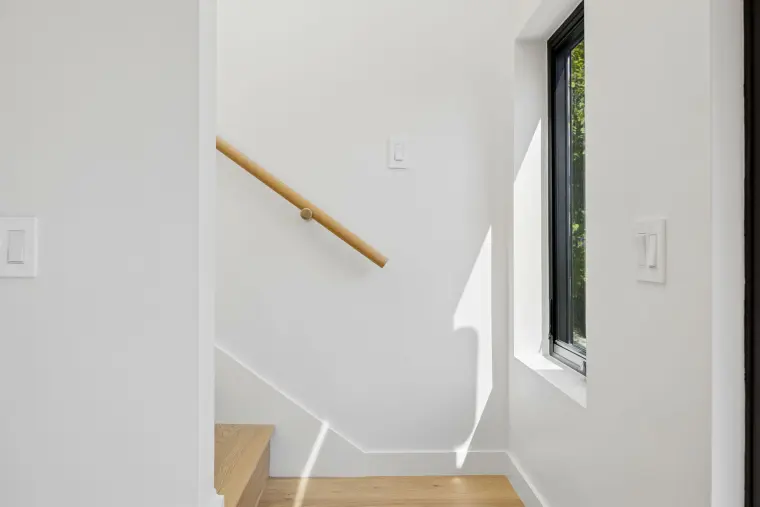 Stairway with an oak handrail and a tall window