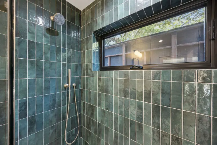 Shower with glossy green tile, a long window, and a handheld sprayer