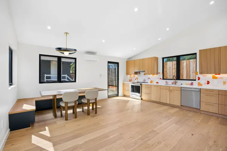 Open kitchen and dining room under a vaulted ceiling with a built-in bench