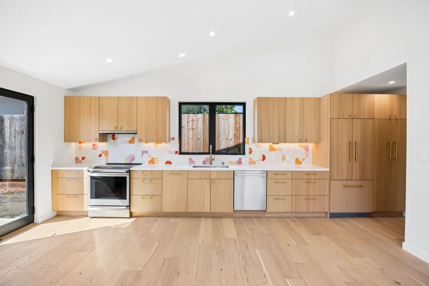 White oak kitchen with a colorful tile backsplash and a panel-ready refrigerator