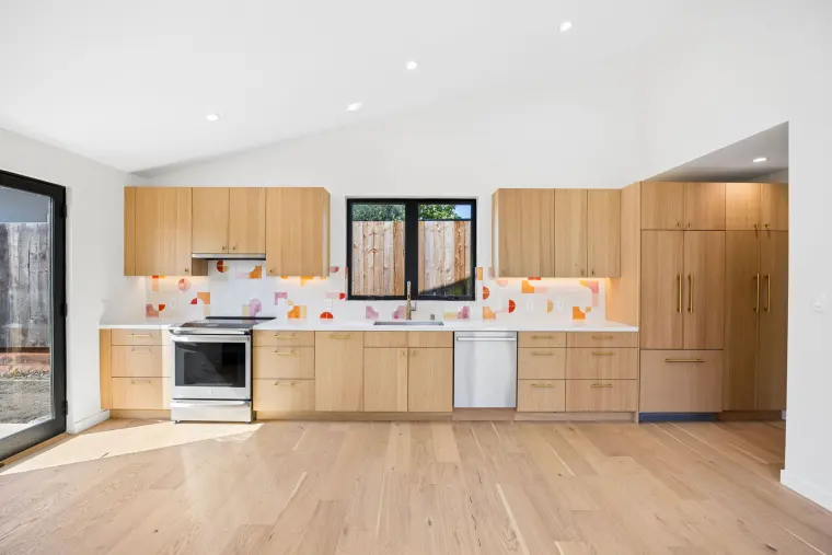 White oak kitchen with a colorful tile backsplash and a panel-ready refrigerator