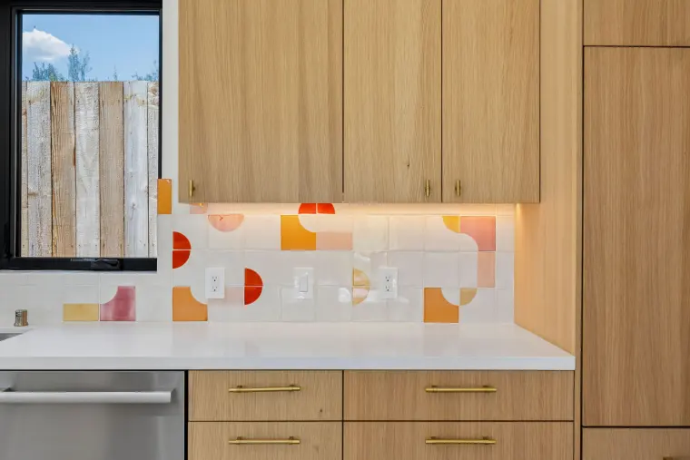Oak cabinets with brass pulls and under-cabinet lights on the patterned tile