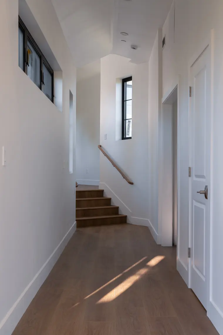 Hallway leading to the stairs, lit by a high window