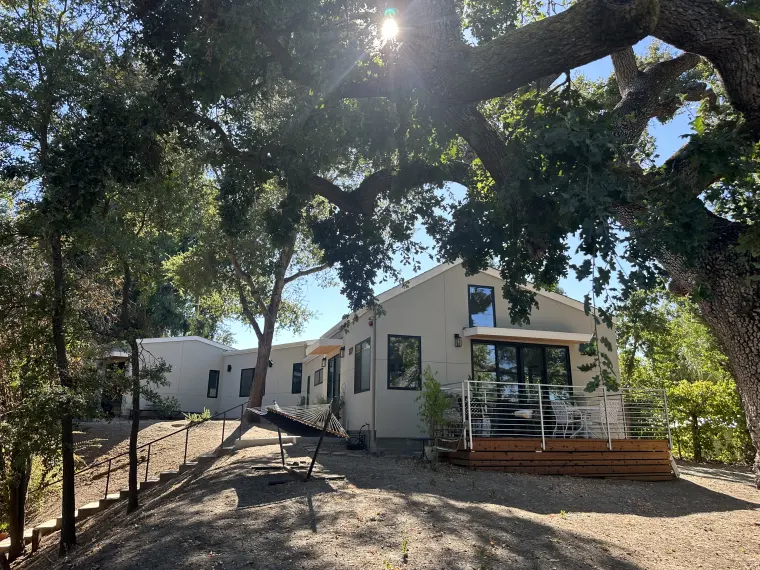 The ADU on its wooded lot, seen from across the oak-shaded yard