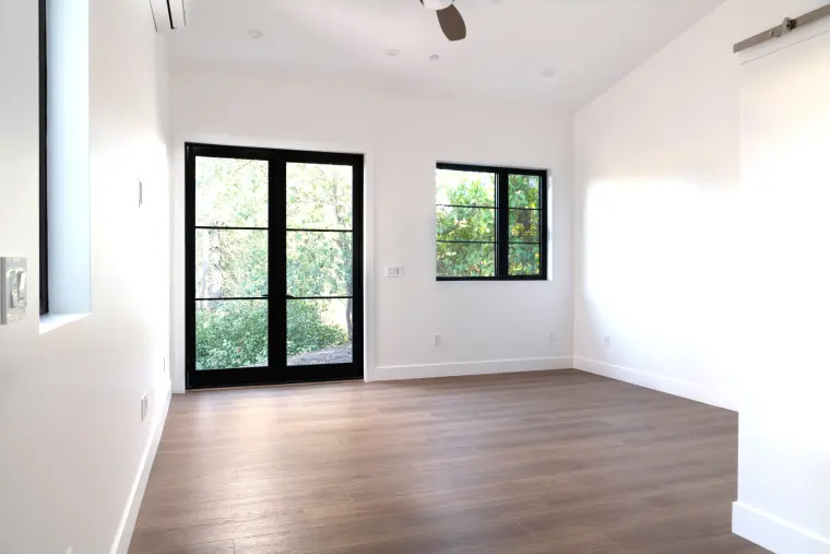 Bedroom with black-framed French doors, a ceiling fan, and wood-look floors