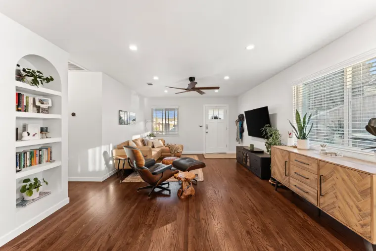 Living room with arched built-in bookshelves, dark hardwood floors, a lounge chair, and a wood media console under a window