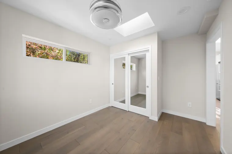 Bedroom with a clerestory window, mirrored closet, and a ceiling fan