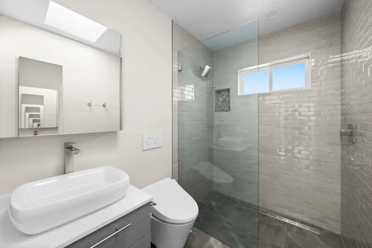 Bathroom with a vessel sink on a floating gray vanity beside a glass shower