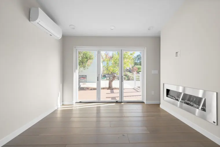 Living room with a linear wall fireplace and glass doors opening to the deck