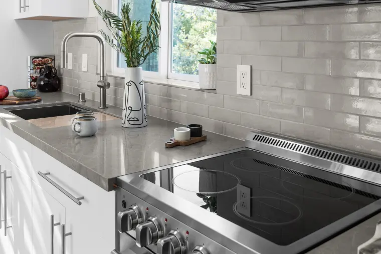 Gray quartz counter with a black glass cooktop, subway tile backsplash, and a brushed faucet