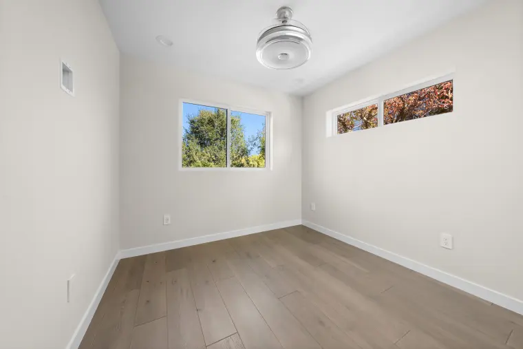 Bedroom with a corner window, clerestory windows, a ceiling fan, and wide-plank floors