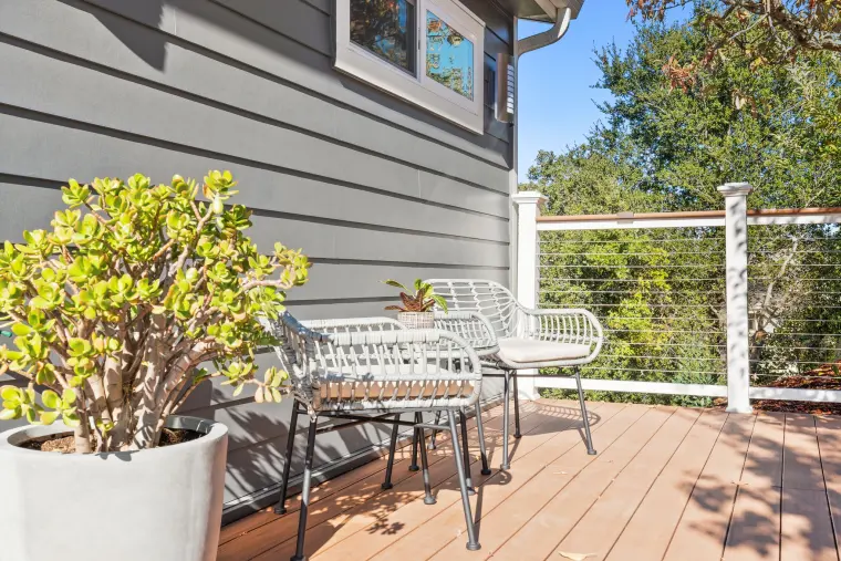 Deck with bistro chairs, potted succulents, and cable railing overlooking the trees