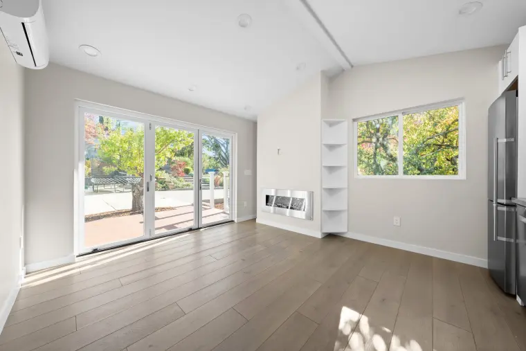 Living room with sliding doors to the deck, a side window, and wide-plank floors