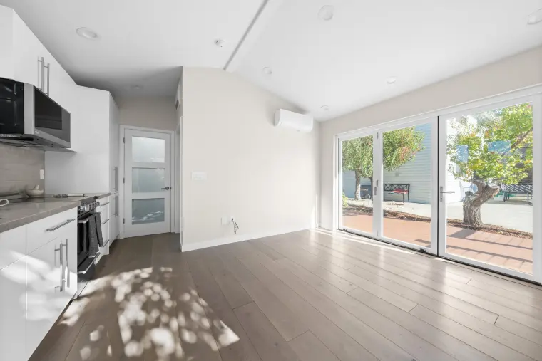 Open living area with the kitchen along one wall and sliding doors to the deck