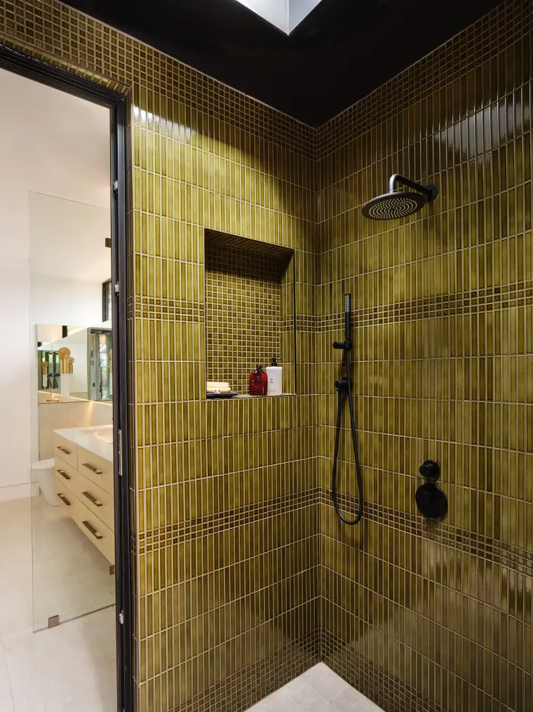 Shower tiled in olive-green glazed tile, open to the sky through a skylight