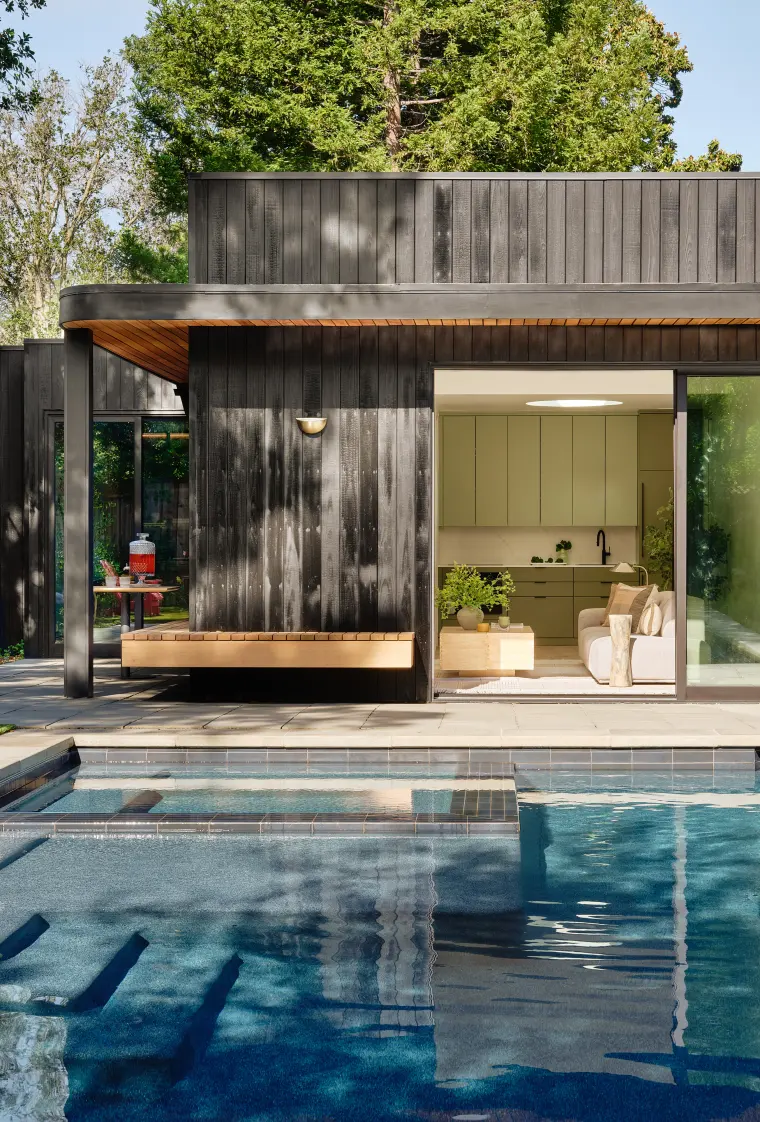 The ADU across the pool, its glass wall revealing the living space inside
