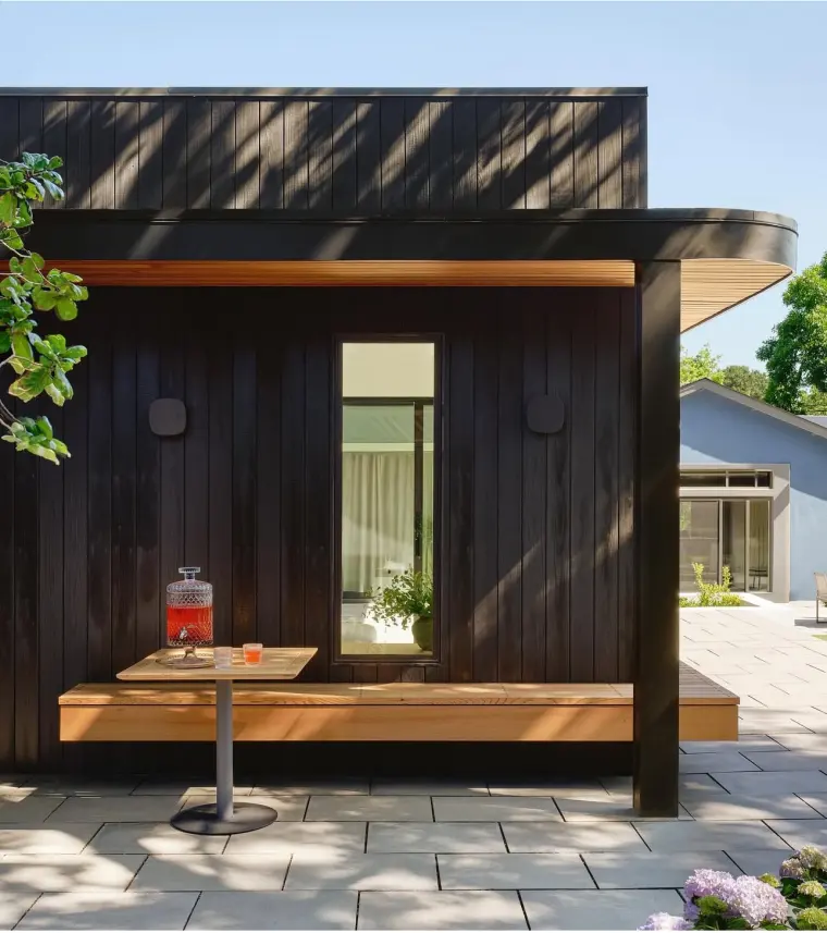 Charred-cedar facade with a built-in bench beneath the roof overhang