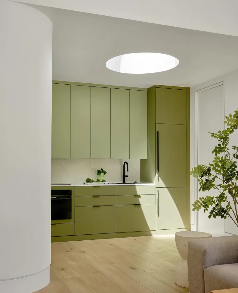 Sage-green kitchen cabinetry under a round skylight
