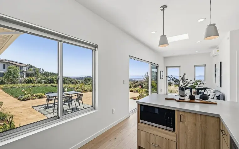 Kitchen peninsula with microwave drawer beside a large picture window and glass door overlooking the patio and hills