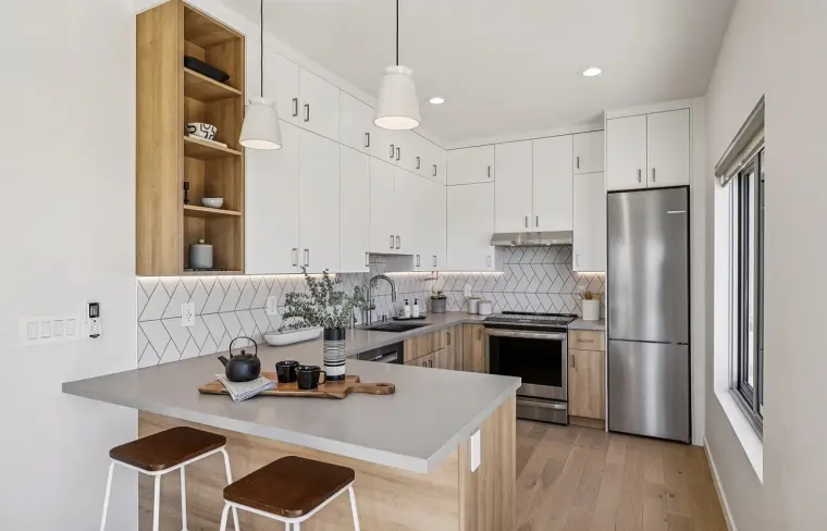 Kitchen with gray peninsula and wood stools, white upper cabinets, open wood shelving, and stainless refrigerator and range