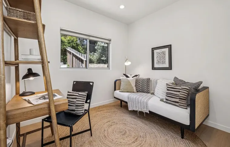 Second bedroom set up as an office with a daybed, leaning ladder desk, and round jute rug under a window