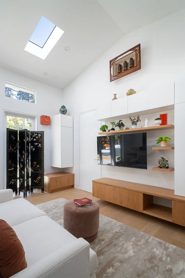 Vaulted ceiling with a skylight over the media wall and oak console, with a lacquered folding screen by the door