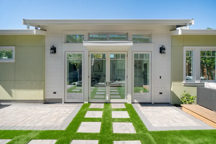 Front of the ADU head-on: French doors under a flat canopy, clerestory windows above, and turf with square stepping pads
