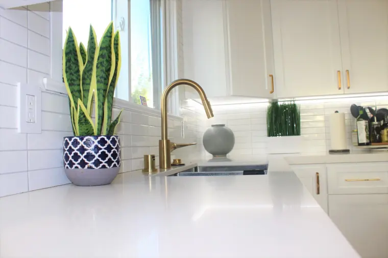 White quartz counter, white subway tile, and a brass faucet at the sink