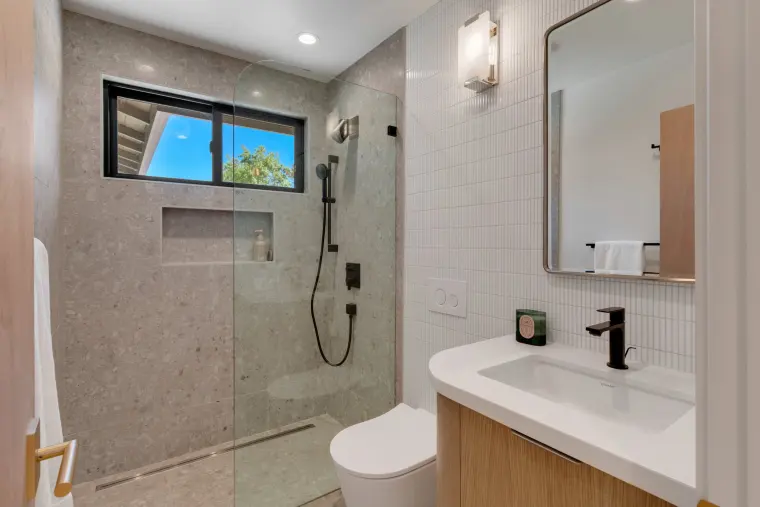 Second bathroom with a terrazzo-look shower, matte black fixtures, and a floating oak vanity
