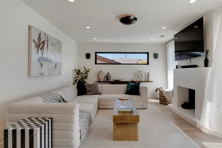Living room with a white sectional, low wood coffee table, and a long black-framed clerestory window