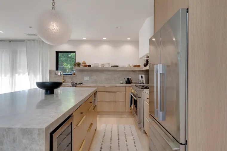 Stone island and pale oak cabinetry looking back toward the living area