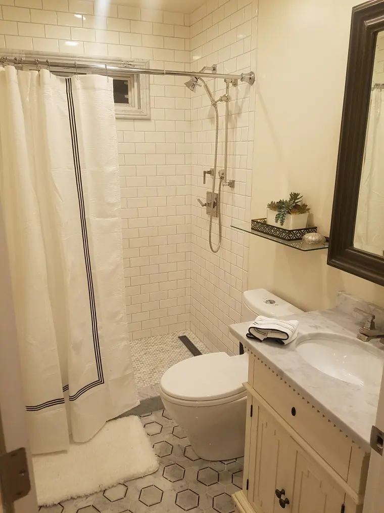 Bathroom with white subway tile, a gray and white hexagon floor, and a white vanity