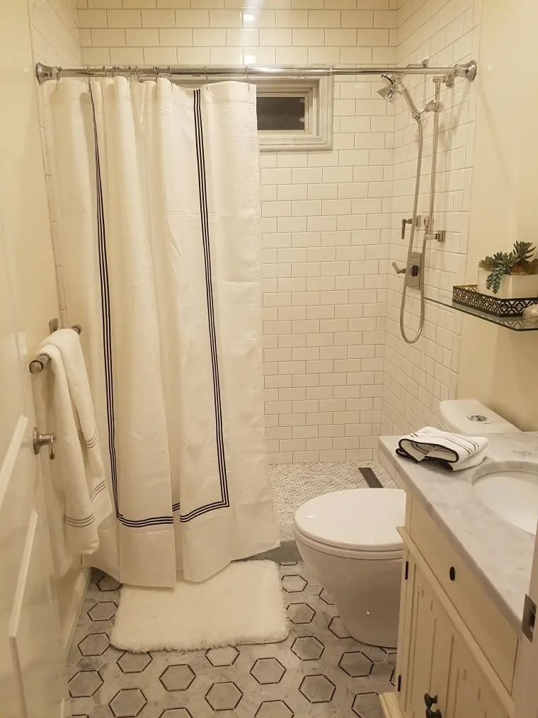 Tiled shower and white vanity with a marble top