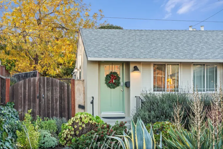 Front of the house: sage-green door with a wreath and a planted front garden