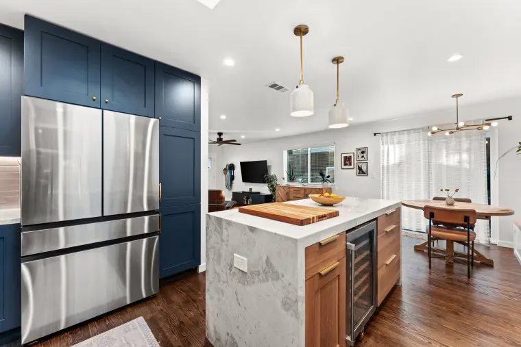 Stainless French-door refrigerator in a navy cabinet surround beside the island, dining area beyond