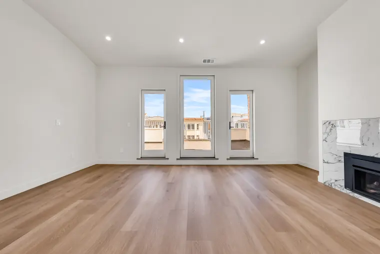 Living room with three tall glass doors, a marble-surround fireplace, recessed lighting, and light oak flooring