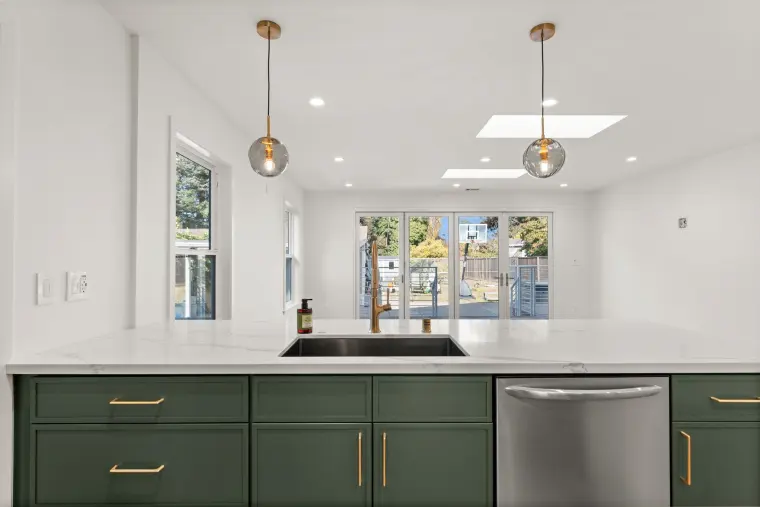 White quartz peninsula with an undermount sink, brass faucet, and smoked glass pendants