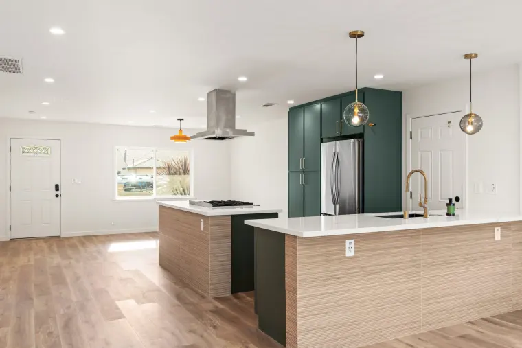 Cooktop island and sink peninsula with wood-look fronts under smoked glass pendants