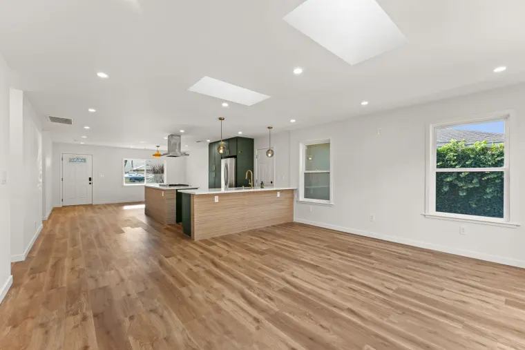 Open living space with skylights, wood-look floors, and the kitchen at the far end