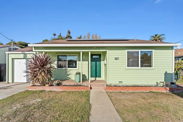 Front of the single-story house in light green lap siding with a teal front door