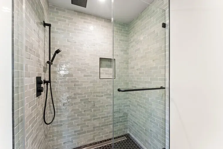 Shower with sage green tile, a wall niche, and black fixtures with a handheld sprayer